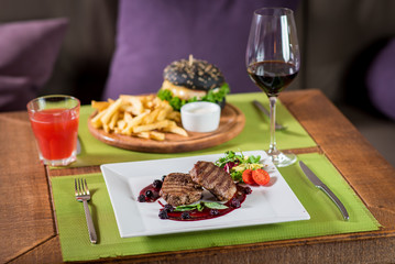 Grilled meat steak with raspberrie sauce on wooden background