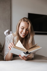 Cheerful young woman reading blank cover open book