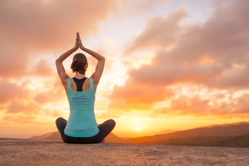 Young woman practicing yoga on a mountain top at sunset. Meditation.
