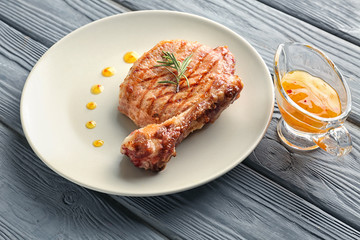 Plate with tasty grilled steak and sauce on wooden table