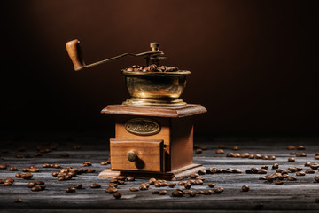 vintage coffee grinder on rustic wooden table spilled with coffee beans