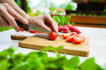 Obraz na płótnie Canvas Healthy eating. Hand slicing tomatoes on wooden cutting board. 