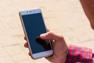 close up on man's hand holding smart phone with blank screen at outdoor