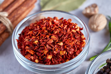 Transparent glass bowl with dried chilly among exotic spicies, close-up, top view, selective focus.