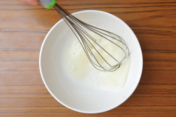 Whipped egg white in a bowl on the table to create a baking cream