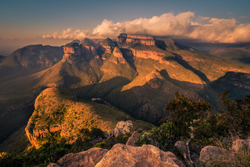 Obraz premium A wide shot of the Three Rondavels and surrounding landscape lit up with dramatic texture and form at sunset golden hour. Mpumalanga, South Africa