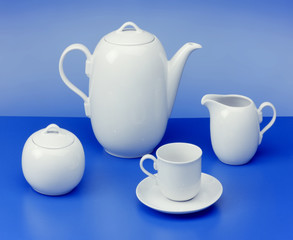 teapot, sugar bowl, cup, milk jug on light blue background
