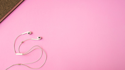 Earphones and notebook on pink  background. Pastel color Minimal concept Copy space