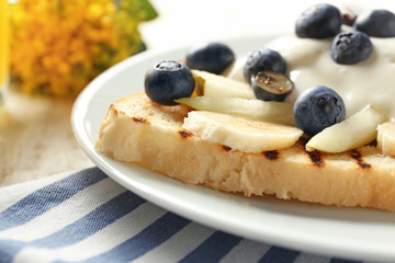 Tasty sweet toast with cream, fruits and blueberry on plate, closeup