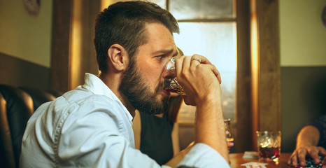 Side view photo of friends sitting at wooden table. Friends having fun while playing board game.