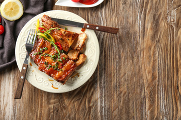 Plate with delicious grilled ribs on table