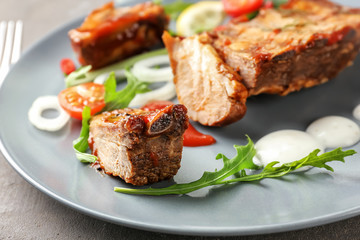 Plate with delicious grilled ribs and sauce on table, closeup