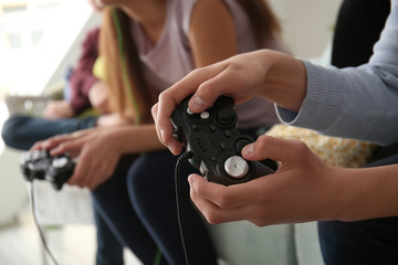 Teenagers playing video games at home, closeup