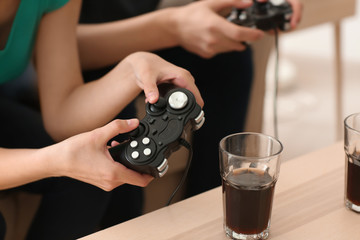 Teenagers playing video games at home, closeup