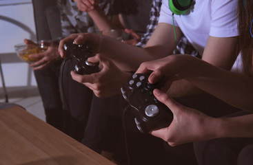 Teenagers playing video games at home late in the evening, closeup