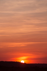 red sunset, the sun sets behind the coastline, a large sky space, beautiful fluffy clouds, a summer evening landscape, the concept