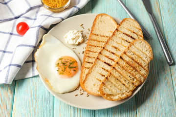 Plate with toasted bread and fried egg on table