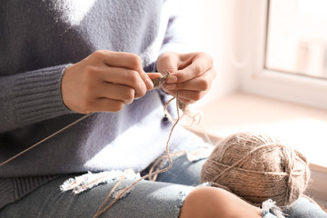 Young woman knitting clothes at home, closeup