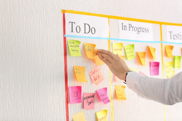Man attaching sticky note to scrum task board in office