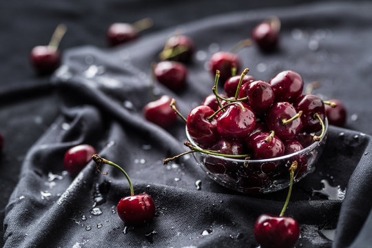 Sweet ripe cherries on dark tablecloth with water drops