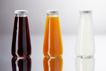 row of bottles of various juice on reflective surface