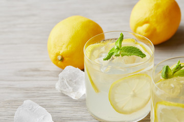 cooled lemonade glasses with ripe lemons on wooden surface