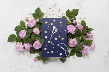 White headphones, Book with a blue cover, small stars and pink r