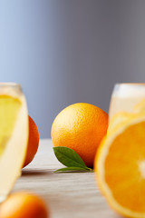 ripe oranges and glasses of cocktail on wooden surface