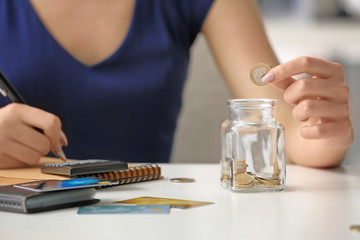 Woman counting coins at table. Savings concept - obrazy, fototapety, plakaty
