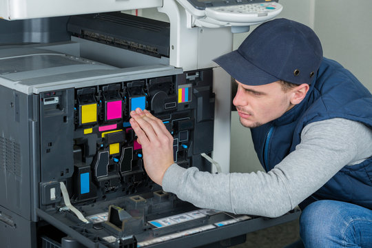 young male technician repairing digital photocopier printer machine
