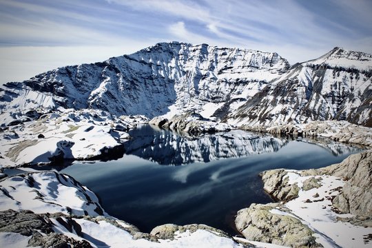 le mont buet dans la vall&eacute;e de chamonix avec sont reflet dans l'eau dans petit lacs a moiti&eacute; gel&eacute; avec de beau cirus dans un ciel bleu 