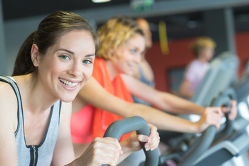group of women riding on exercise bike in gym