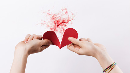 Woman hands tearing paper heart with red fractal effect