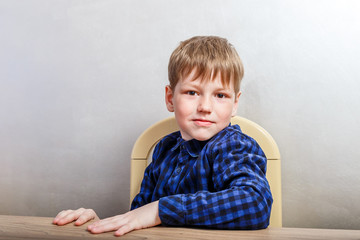 Naklejka premium seven-year-old boy in dark shirt sitting at the table