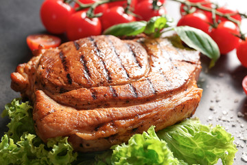 Tasty grilled steak with vegetables on grey background