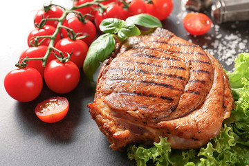 Tasty grilled steak with vegetables on grey background