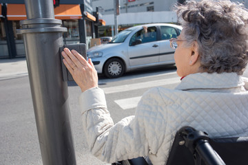 senior female on a wheelchair pushing button for traffic light