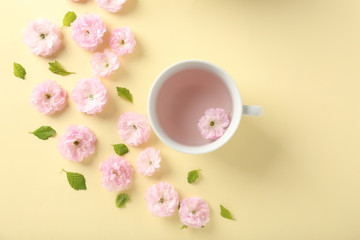 Composition with cup and blossoming flowers on color background