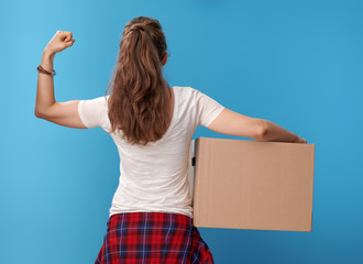 modern woman with cardboard box showing biceps on blue - obrazy, fototapety, plakaty