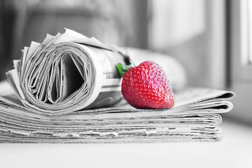 Stack of newspapers and strawberries. Daily journals with headlines and articles and fresh fruits....