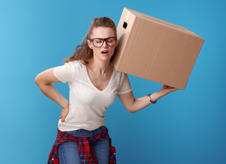 modern woman with cardboard box having backache on blue