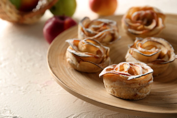 Tasty apple roses from puff pastry on wooden plate