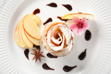 Tasty apple rose from puff pastry with chocolate sauce on plate