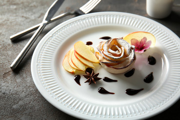 Tasty apple rose from puff pastry with chocolate sauce on plate