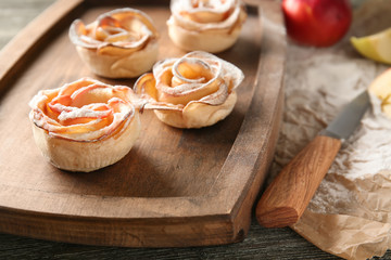 Obraz na płótnie Canvas Tasty apple roses from puff pastry on wooden board