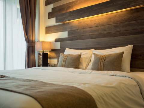 Empty double bed and lamp on side of bed in luxury and natural style bedroom is decorated with wooden boards.