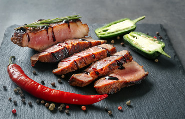Sliced tasty steak with chili and spices on slate plate