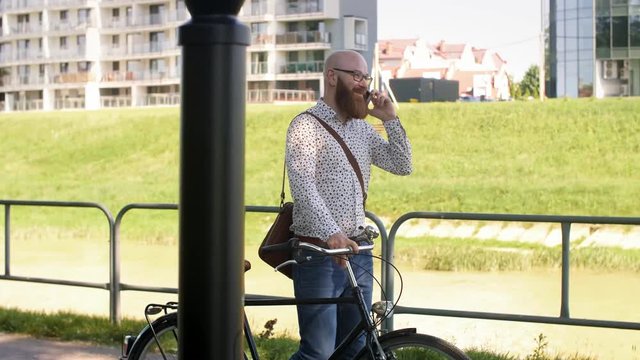 Businessman with bicycle talking by mobile phone