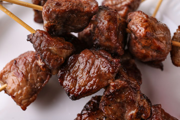 Barbecue skewers with juicy meat on plate, closeup