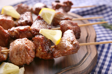 Barbecue skewers with juicy meat on wooden board, closeup